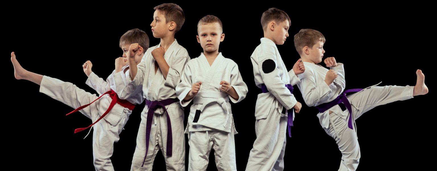 Group of boys, children training martial arts, karate isolated over black studio background. Sportive lifestyle